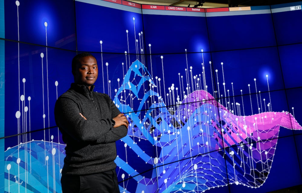 A student posses in front of the screens showing a data image in the EVL lab.