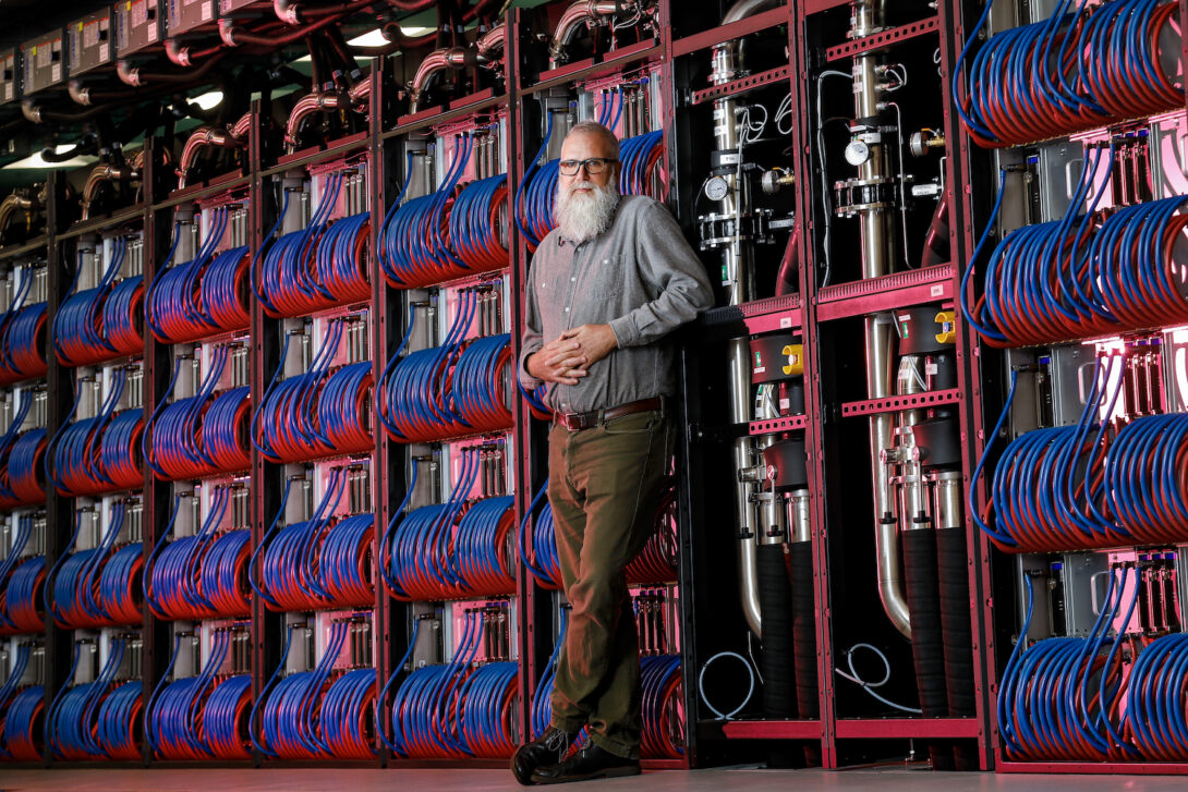 Michael E. Papka, a professor in UIC’s computer science department, stands with the Aurora supercomputer at Argonne National Laboratory.