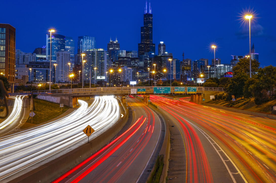 A night image of a Chicago's downtown, with headlights and tail lights streaming down the highway